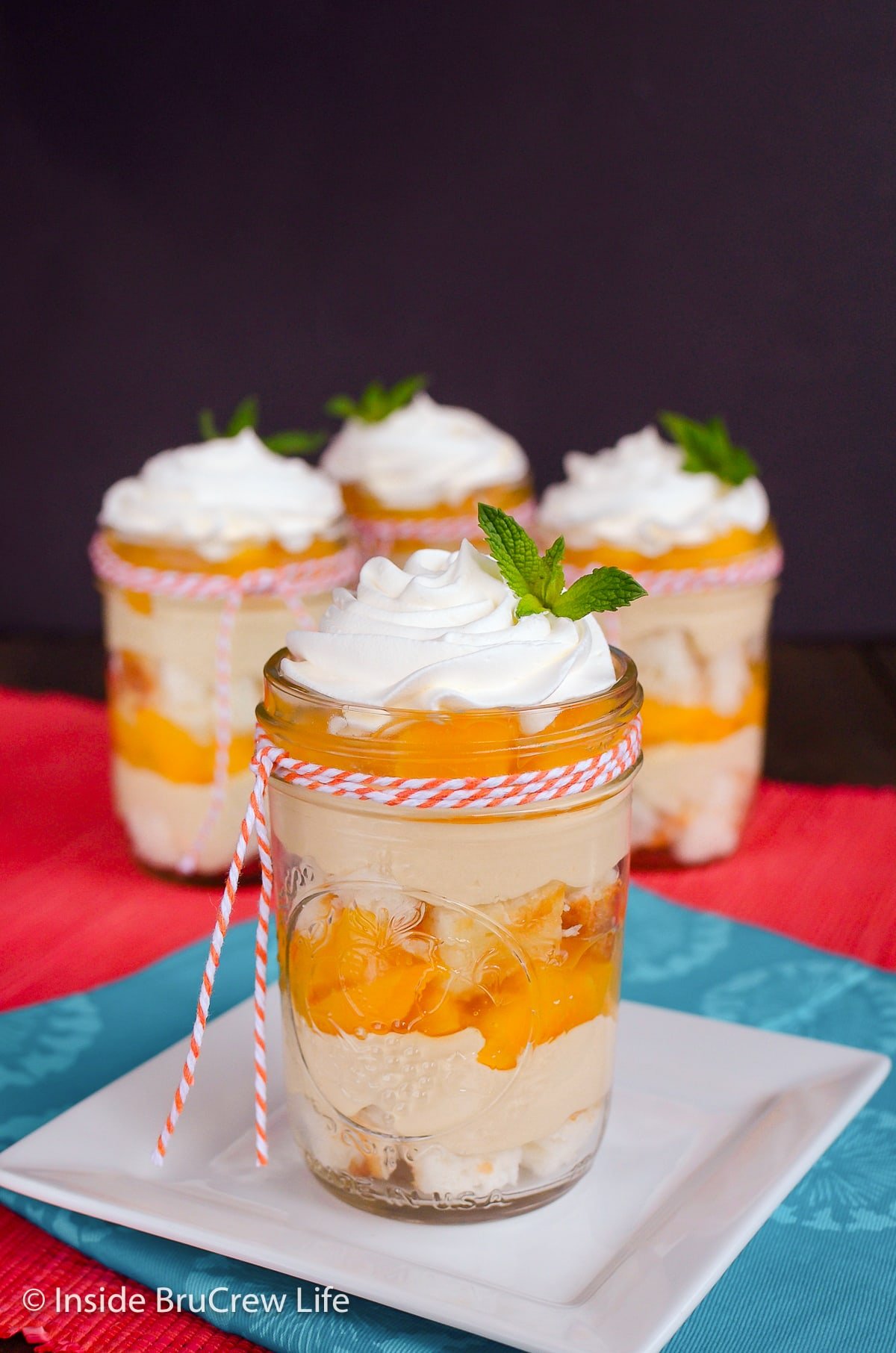 Four clear jars filled with cake, no bake cheesecake, and pie filling.