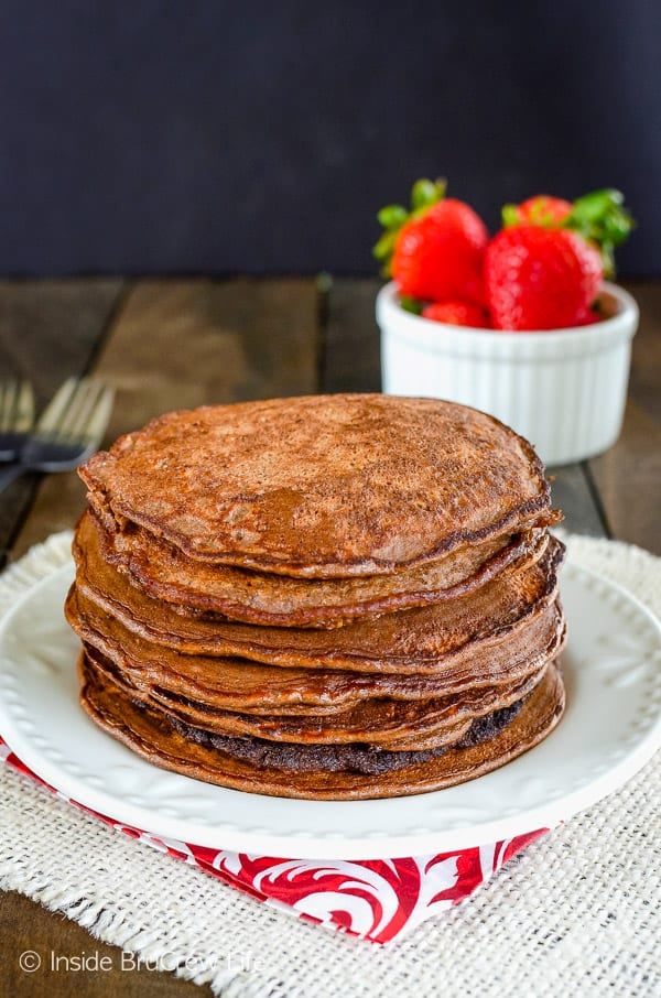 A stack of chocolate pancakes on a white plate.