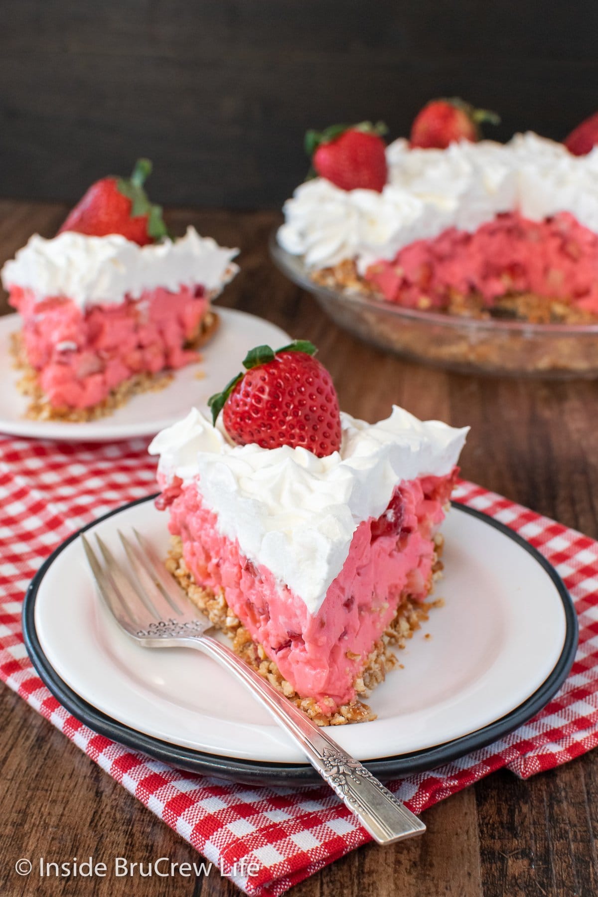 Two white plates with slices of creamy pink Jello pie on them.