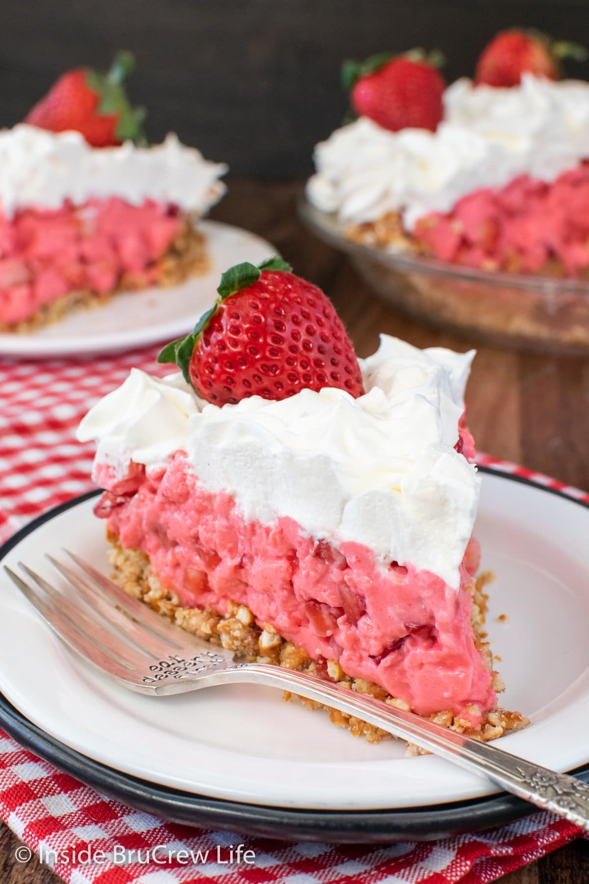 A slice of creamy pink Jello pie on a white plate.