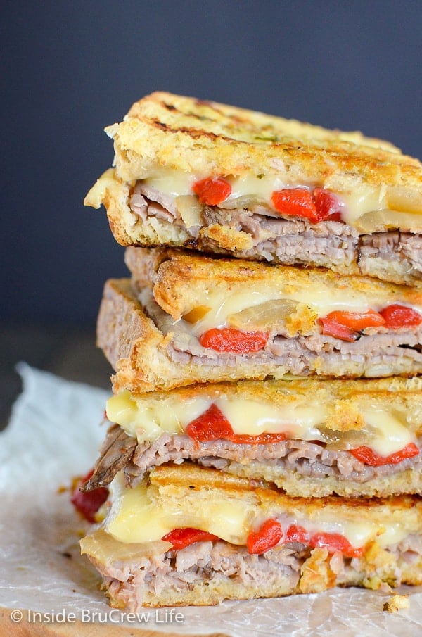 A close up picture of a stack of Cheesy Beef Panini sandwiches on a cutting board
