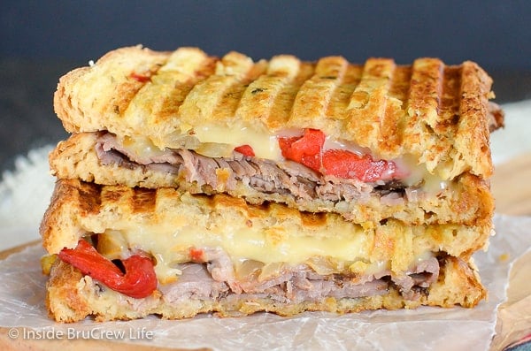 Two halves of a cheesy beef panini on a cutting board