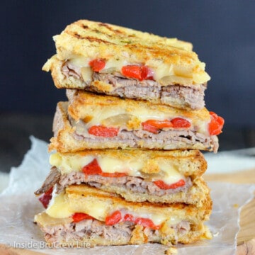 Four squares of cheesy beef panini stacked on top of each other on a cutting board