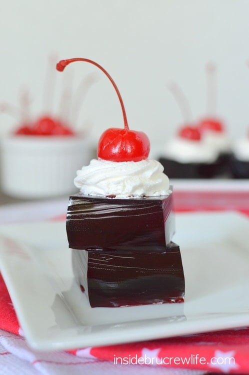 Two Jello squares stacked on a white plate.