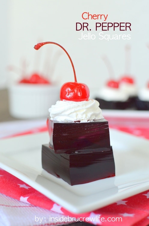 A stack of Jello squares topped with whipped cream and a cherry.