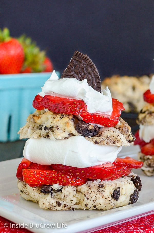 Close up pictures of two layers of coconut Oreo strawberry shortcakes on a white plate with fresh strawberries and whipped cream