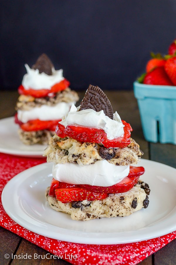 Two Coconut Oreo Strawberry Shortcakes on a white plate layered with whipped cream and fresh berries