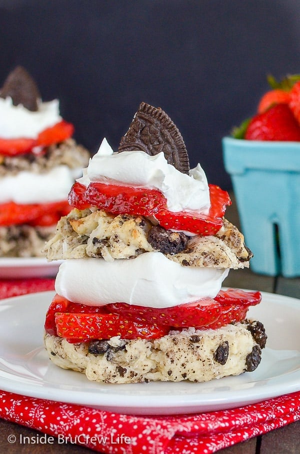 Close up picture of Coconut Oreo Strawberry Shortcakes on a white plate layered with whipped cream and fresh strawberries