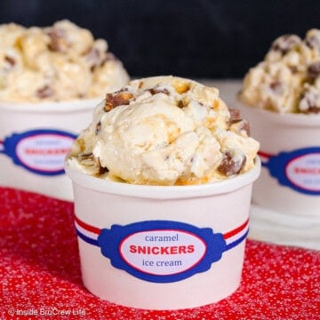 A scoop of Snickers ice cream in a white paper container.