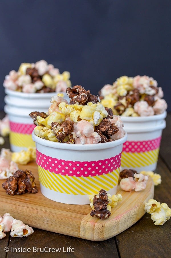 Three white bowls with pink and yellow stripes filled with banana split popcorn