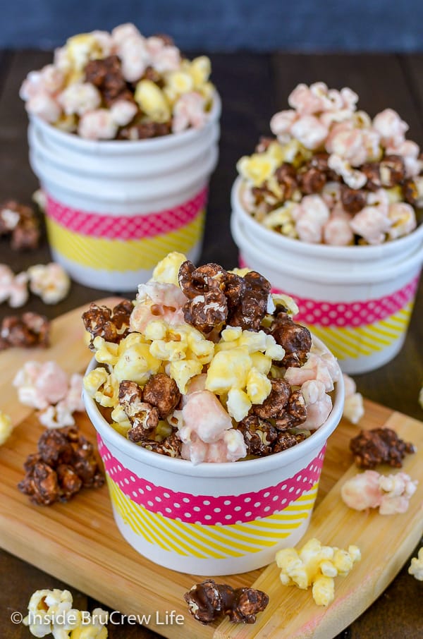 Three white bowls filled with chocolate, banana, and strawberry flavored popcorn