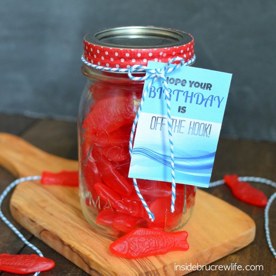 A mason jar filled with Swedish fish and a printable birthday tag tied on with blue and white twine