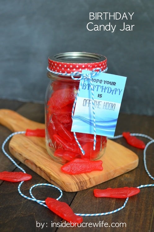 A mason jar filled with Swedish fish  with a printable birthday tag tied on with blue and white twine