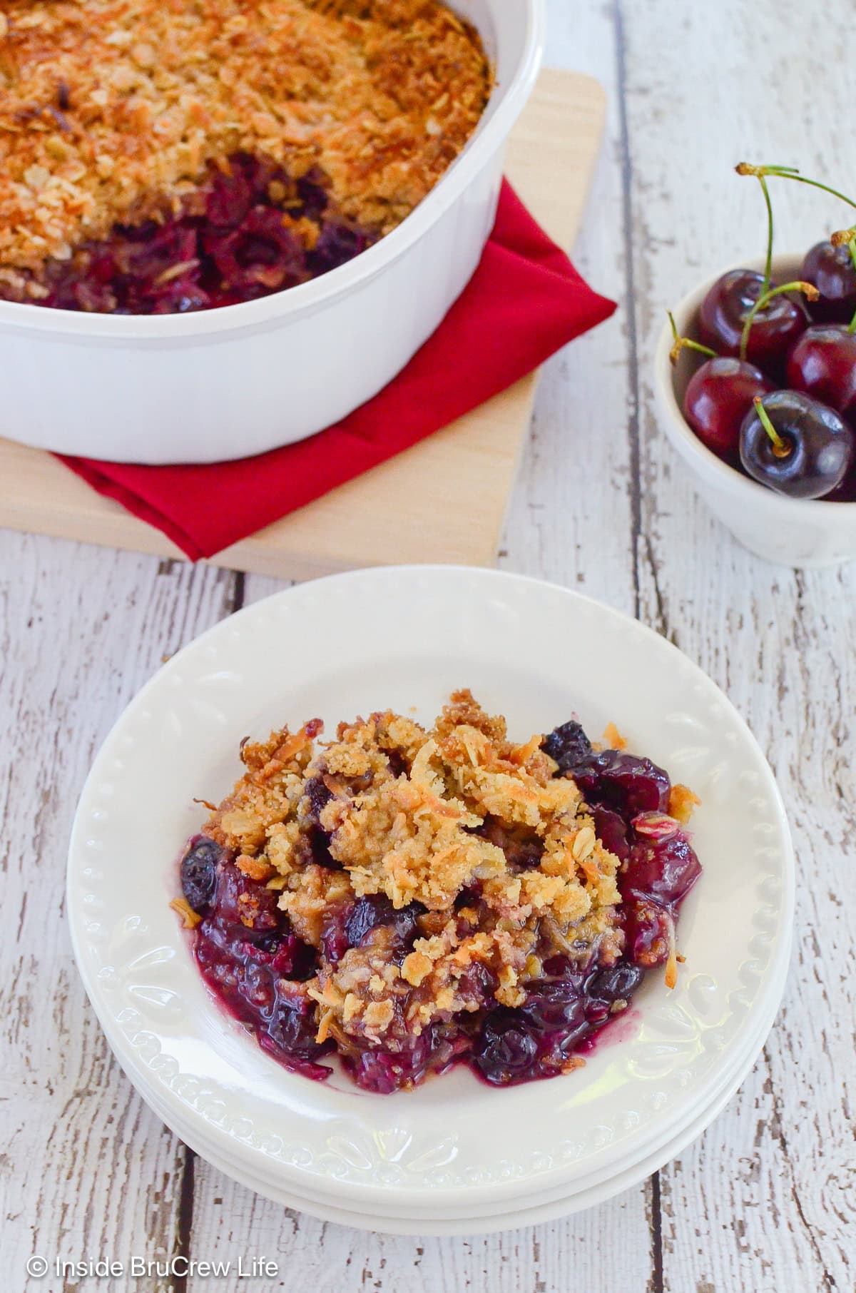 A white bowl filled with fruit and a crispy topping.