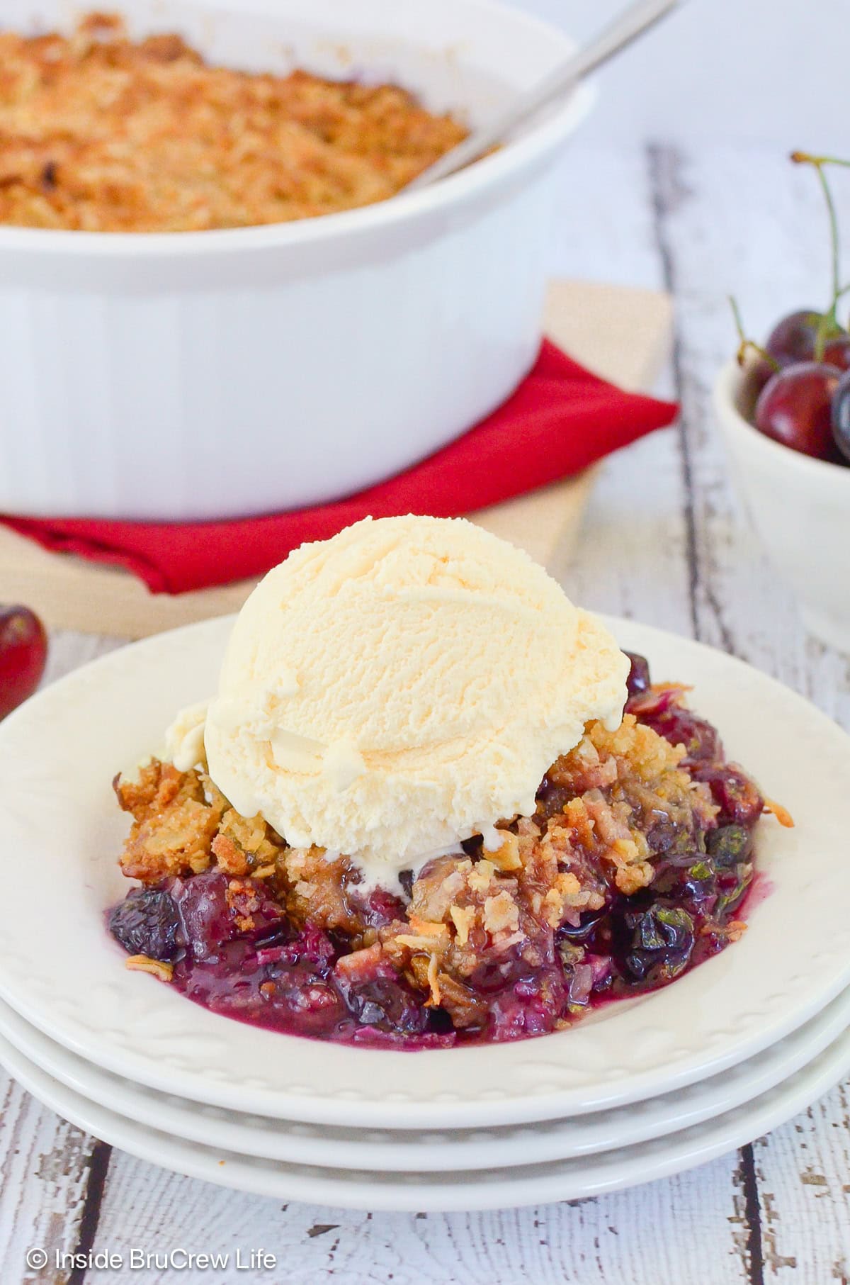 A serving of berry cherry crisp topped with vanilla ice cream.