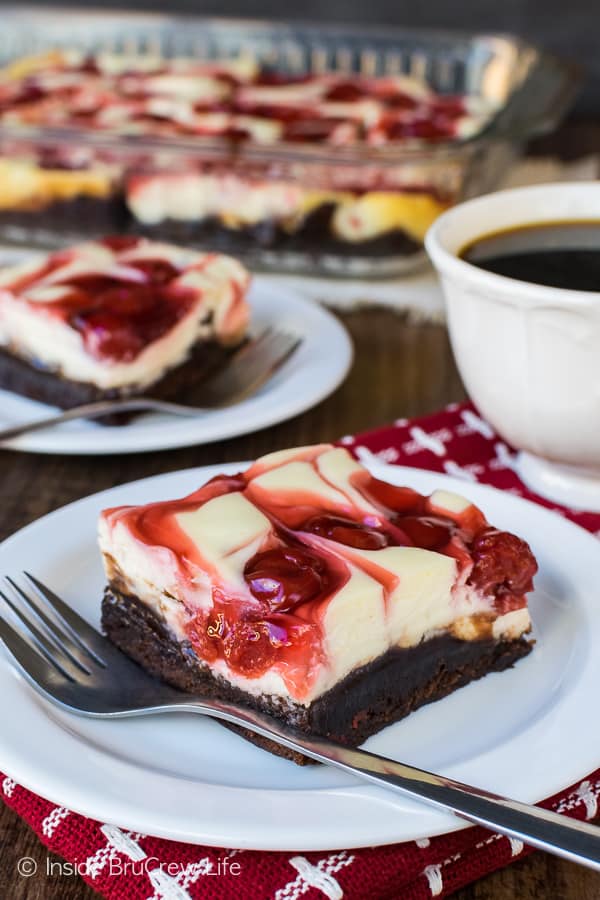 Two white plates with forks and squares of cherry cheesecake swirled brownies on them