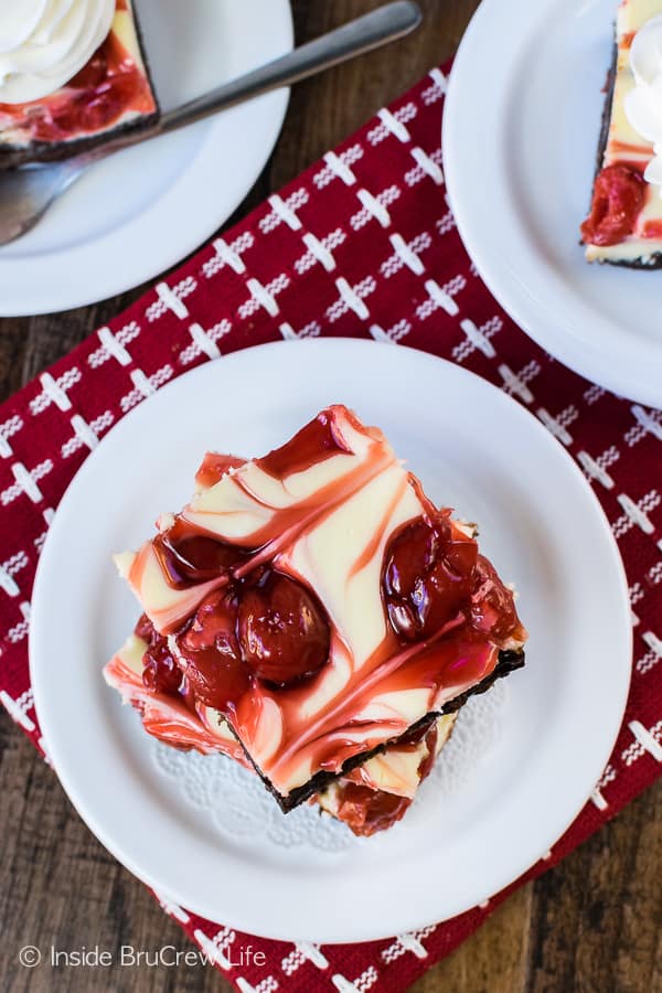 Overhead picture of a white plate with two squares of cherry cheesecake brownies stacked on it