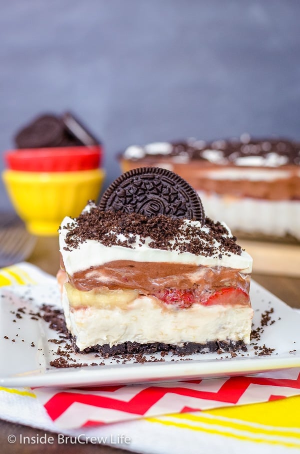 A square of banana split lasagna on a plate topped with Oreo cookies and crumbs.