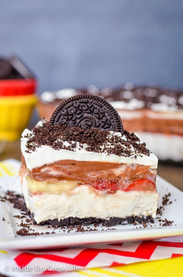 A square of banana split lasagna on a plate topped with Oreo cookies and crumbs.