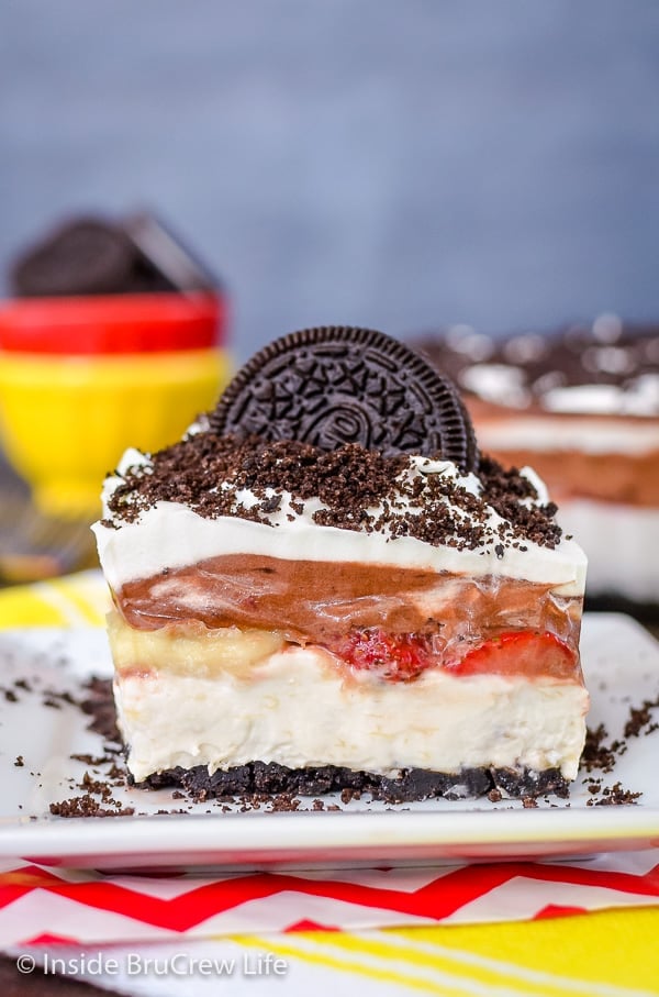 A square of banana split lasagna on a plate topped with Oreo cookies and crumbs.