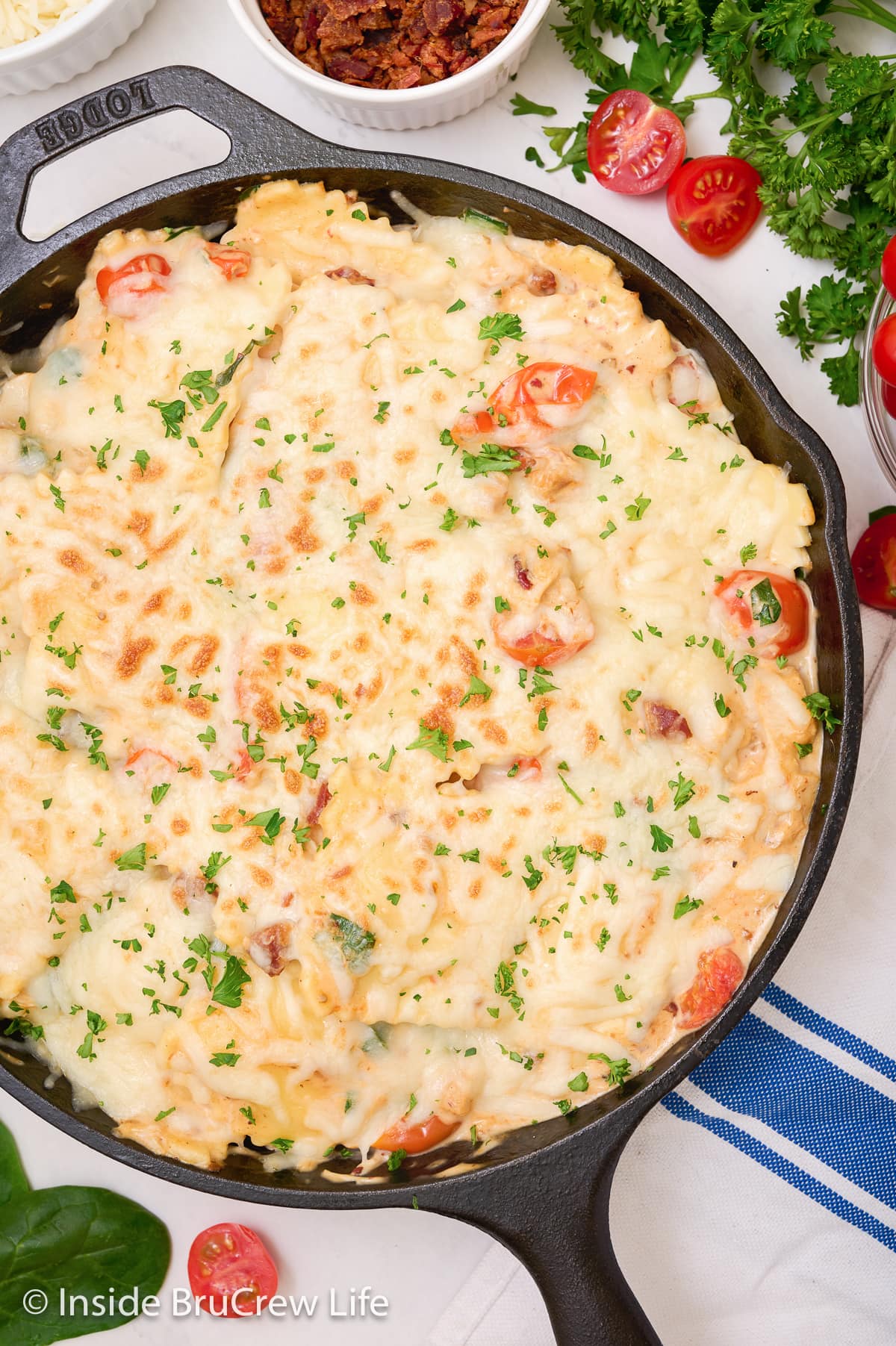 A skillet filled with ravioli covered with toasted melted cheese.