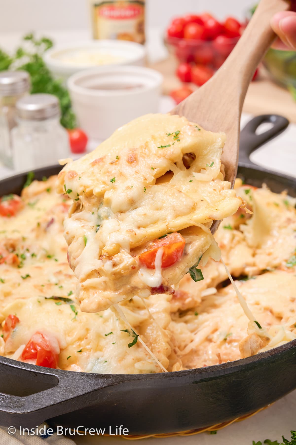 A spoon lifting cheesy ravioli out of a pan.