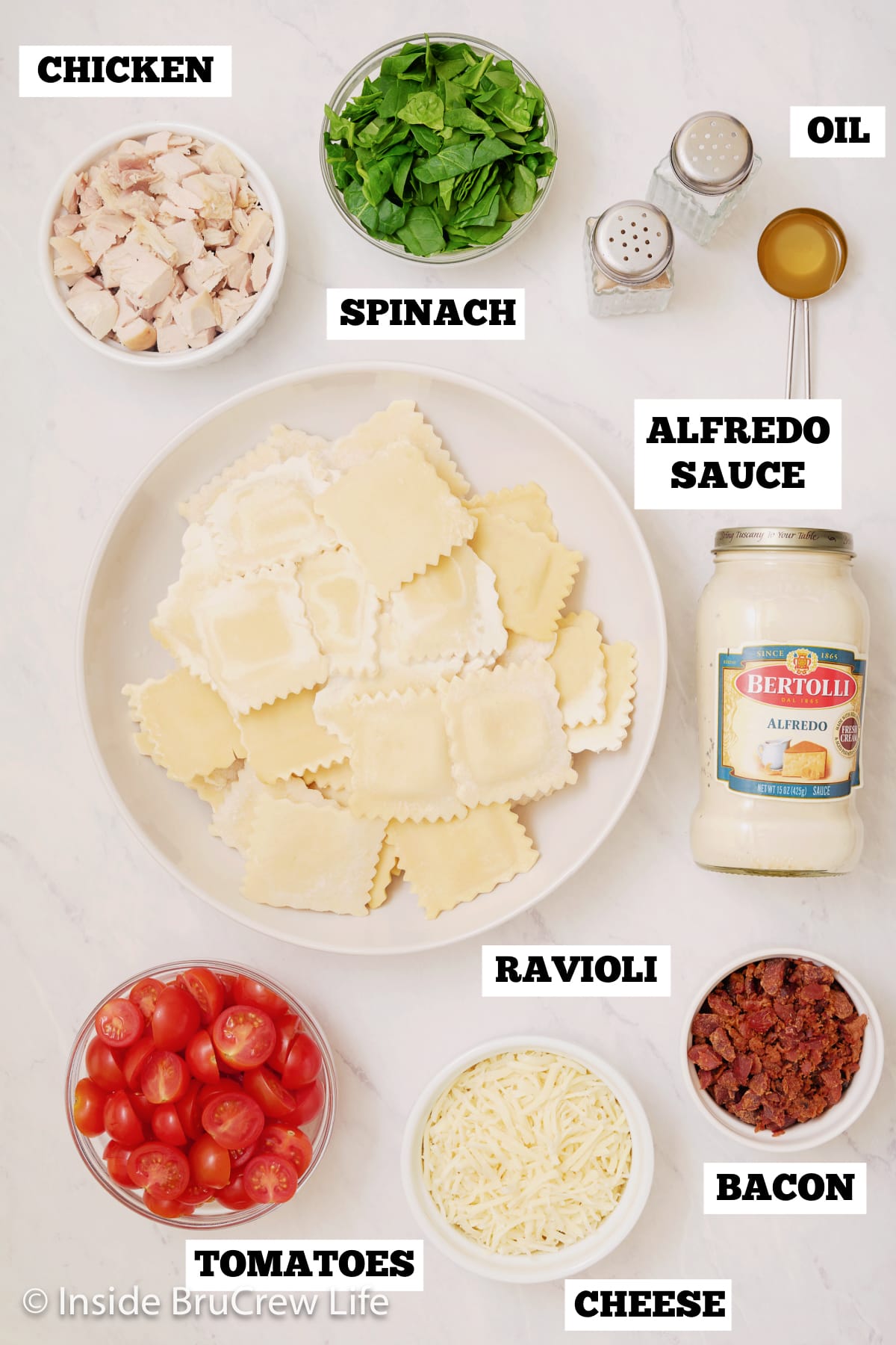 A white board with bowls of ingredients needed to make a skillet ravioli dinner.