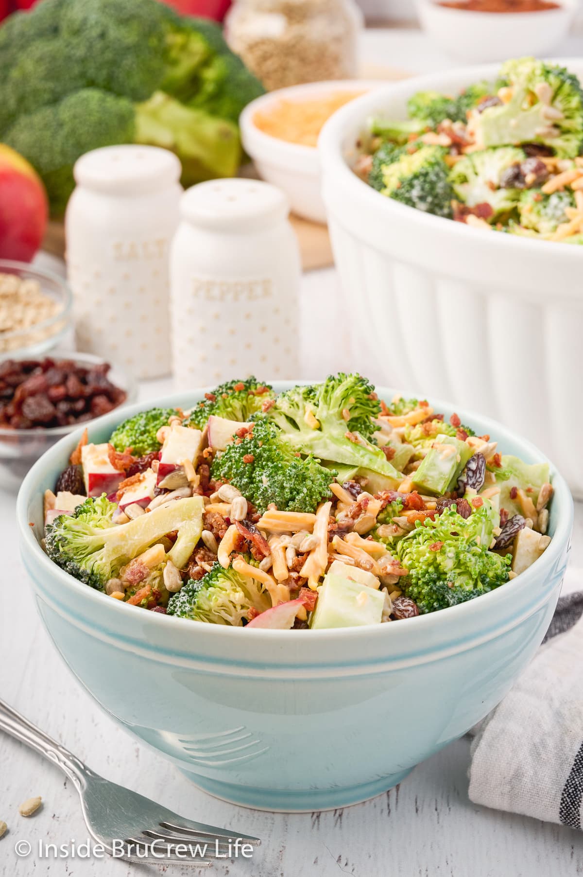 A small blue bowl filled with a a crunchy green salad topped with bacon.