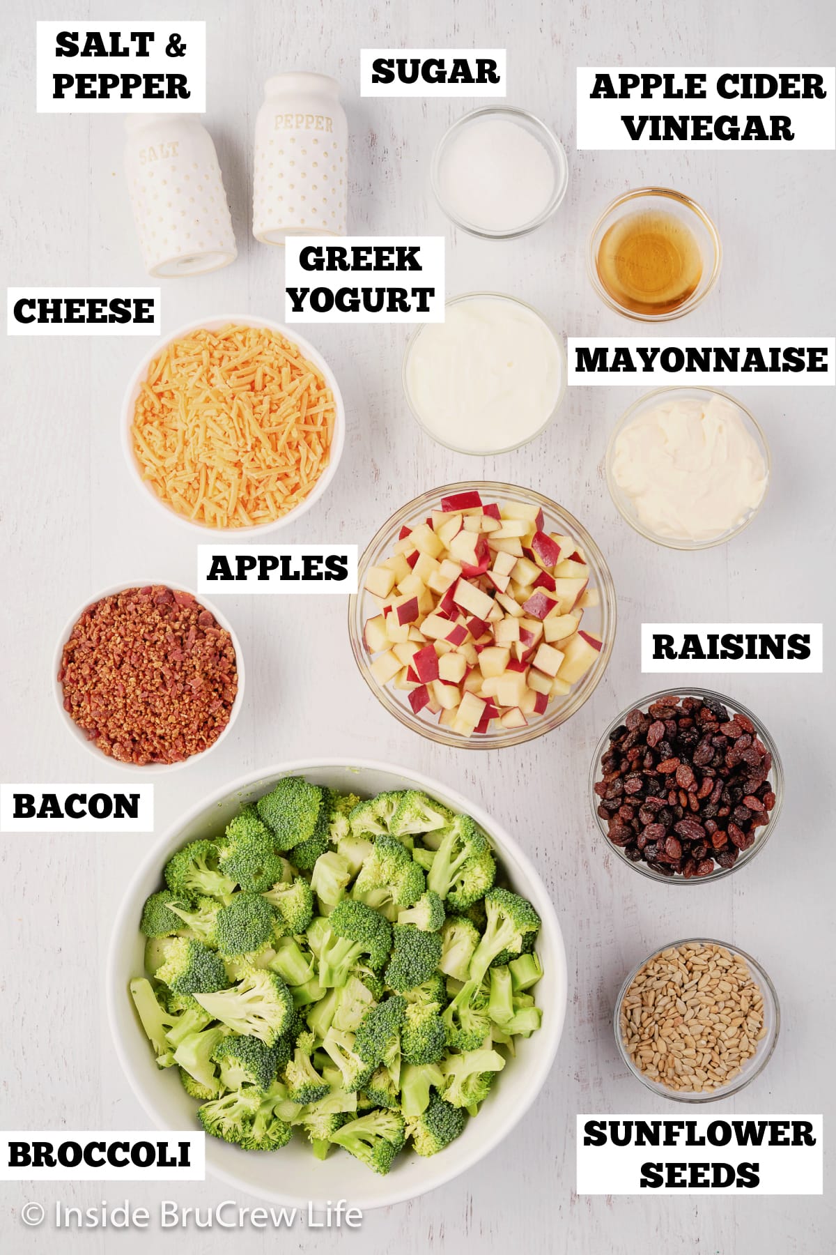 A white board with bowls of ingredients needed to make a broccoli salad.