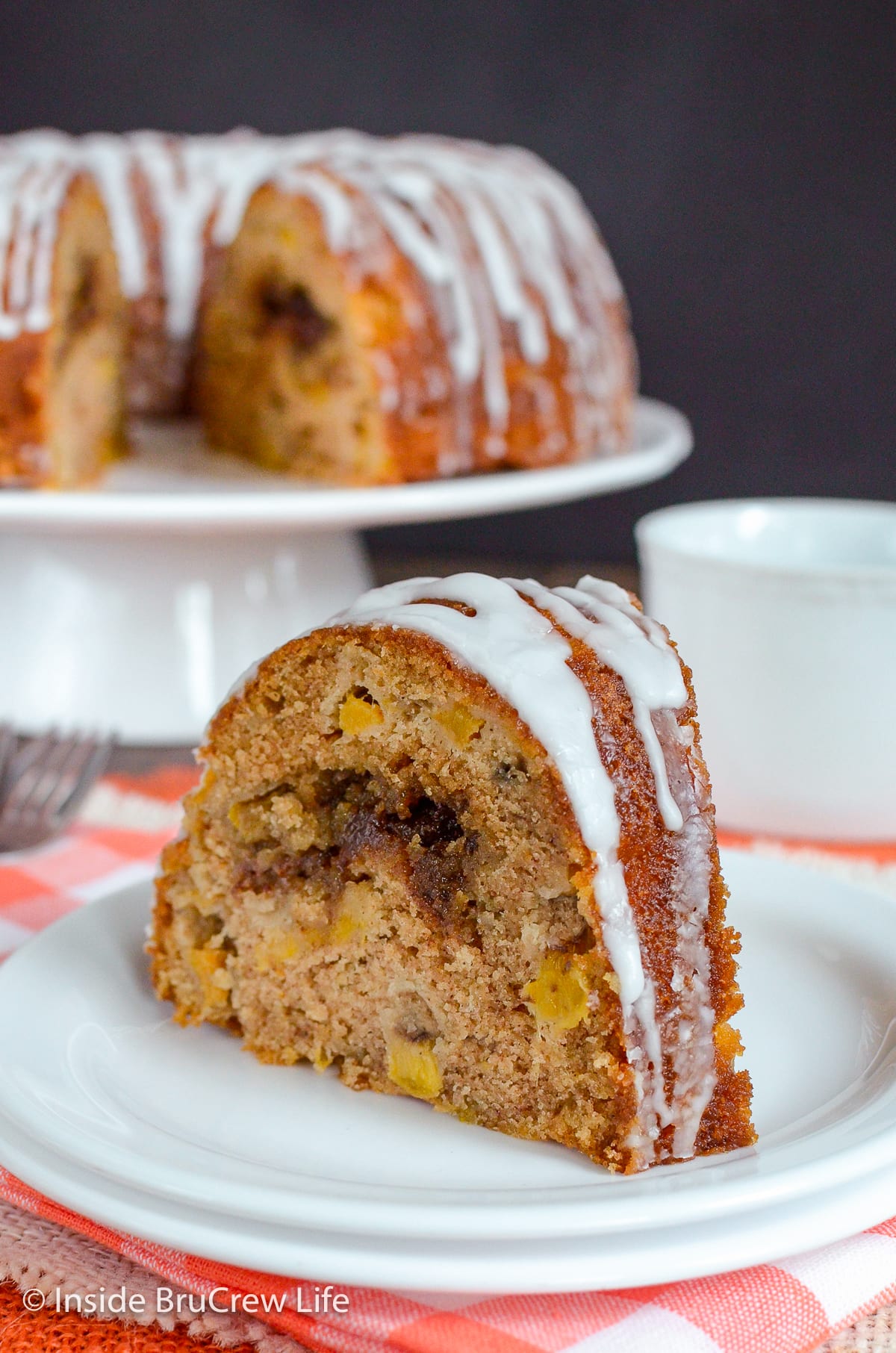 A slice of glazed peach cake on a white plate.