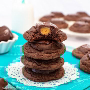 A stack of brownie cookies with one on top missing a bite and showing the gooey caramel center.
