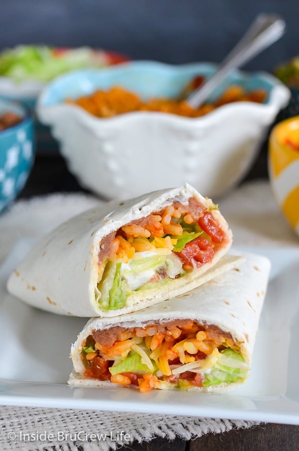 A seven layer burrito cut in half facing forward on a white plate