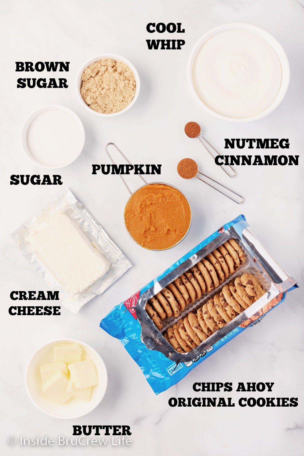 A white board with bowls of ingredients to make a no bake pumpkin pie.