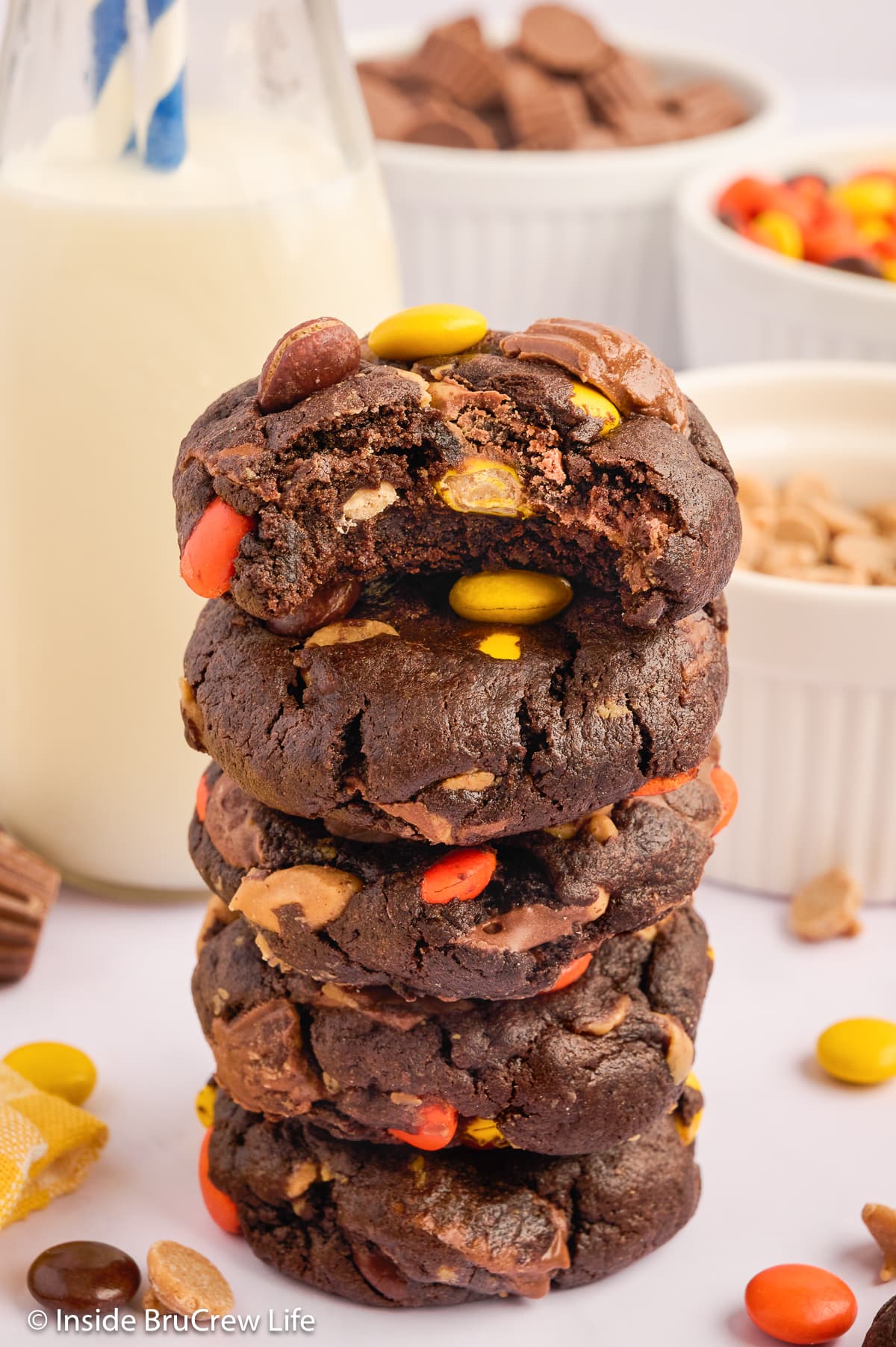 A stack of chocolate candy cookies with a bite taken out of the top cookie.