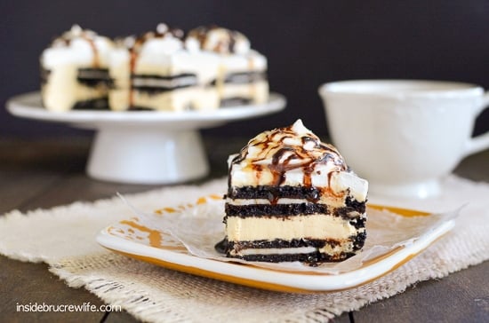 A plate with a piece of salted caramel Oreo icebox cake on it and a cake plate with more cake behind it