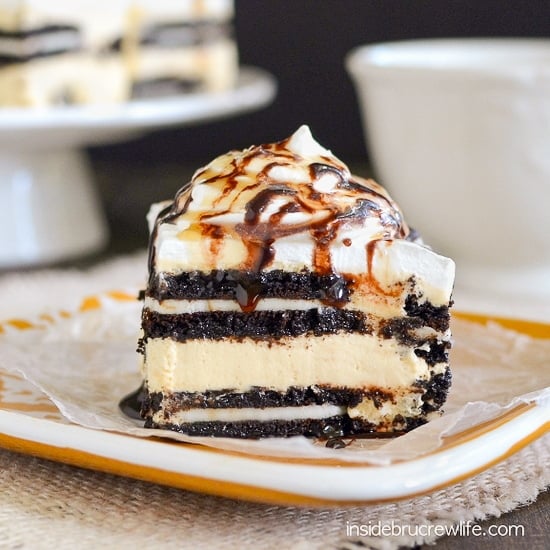 A square of salted caramel Oreo icebox cake topped with whipped cream and chocolate syrup on a yellow plate