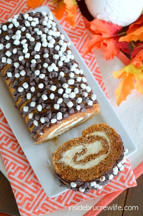 S'mores Pumpkin Roll - the classic pumpkin roll gets a delicious twist with marshmallow frosting and chocolate drizzles. Easy recipe to make this fall. #pumpkin #cakeroll #fall #smores #thanksgiving