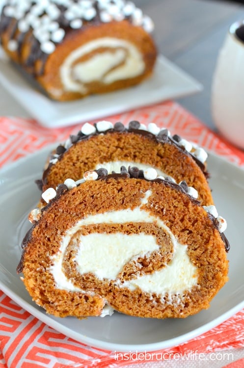 S'mores Pumpkin Roll - marshmallow frosting and chocolate drizzles give the classic pumpkin roll a delicious flair. Easy recipe to make for dinners this fall. #pumpkin #cakeroll #fall #smores #thanksgiving