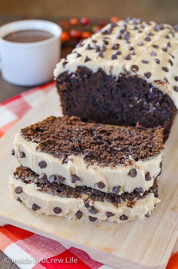 A cutting board with slices of chocolate bread topped with caramel frosting on it.
