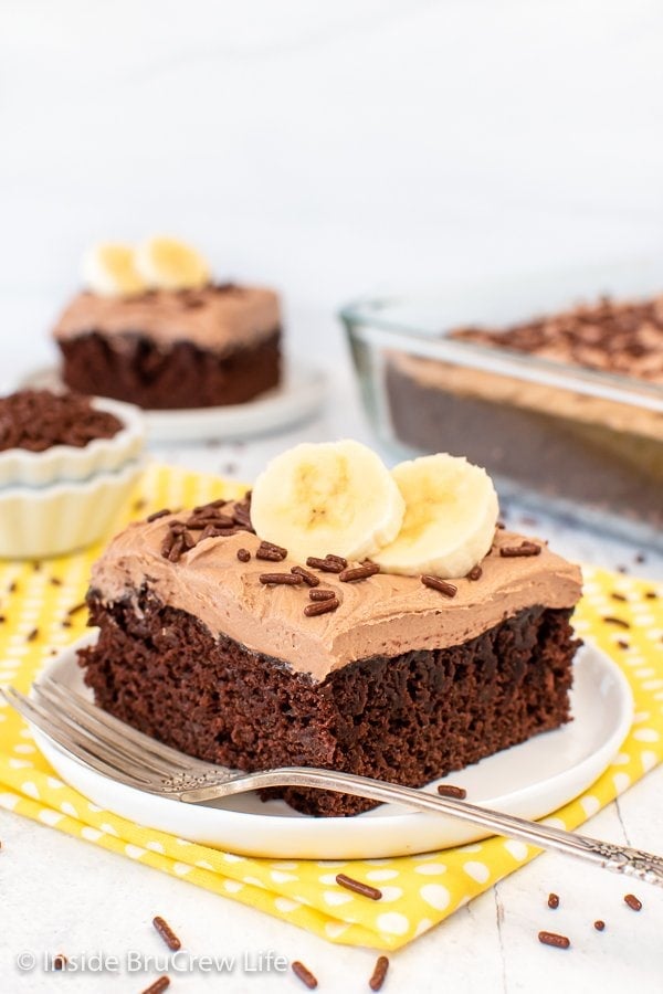 A slice of chocolate cake topped with frosting and banana slices.