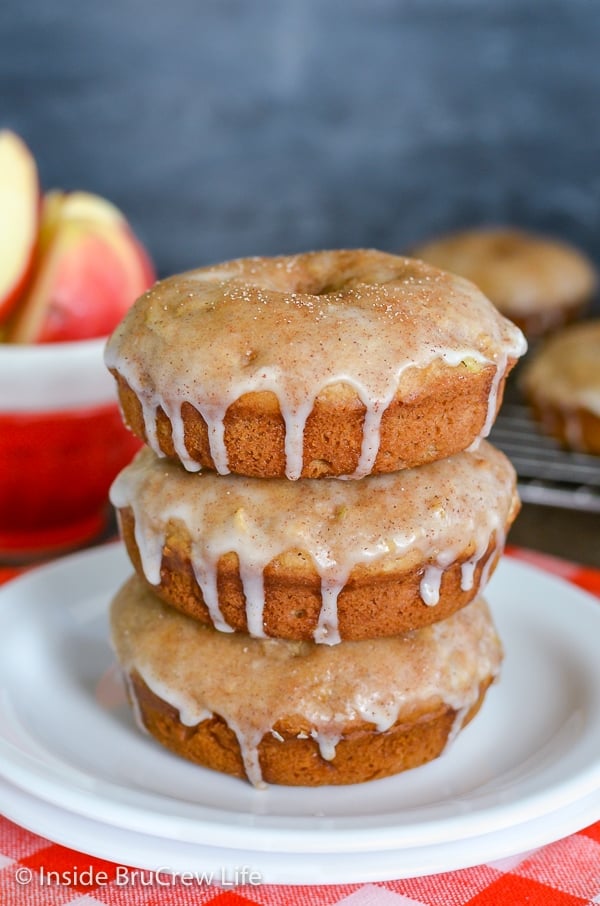 A white plate with three glazed cinnamon apple donuts stacked on it