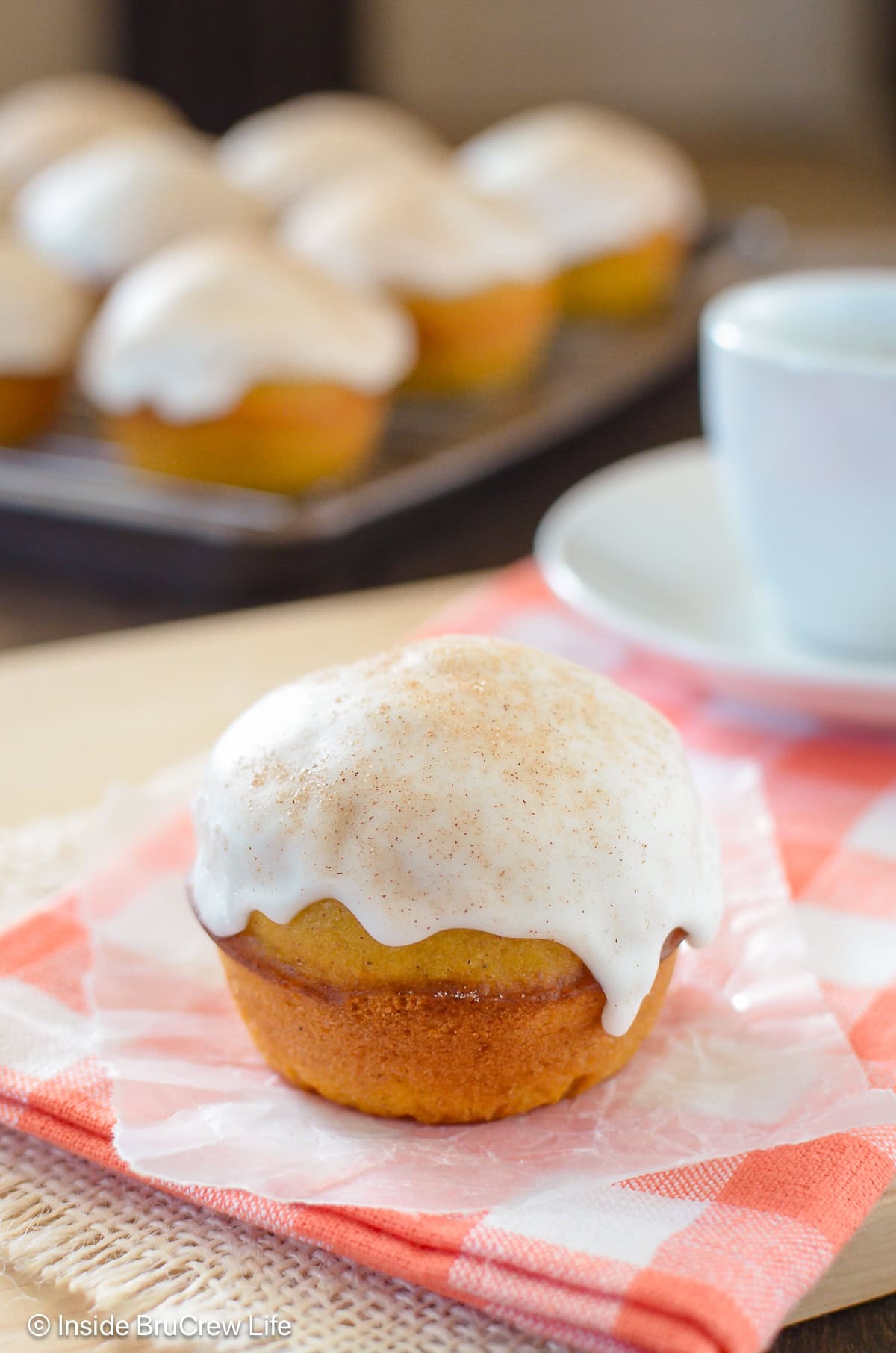 A glazed pumpkin muffin on an orange towel.