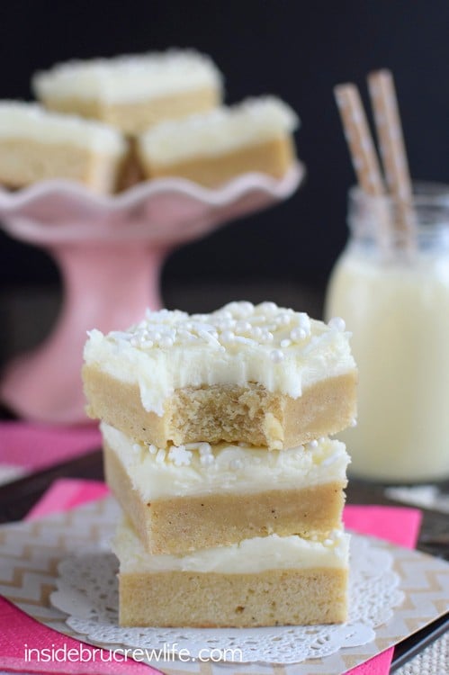 Three eggnog sugar cookie bars with frosting and sprinkles stacked on top of each other.