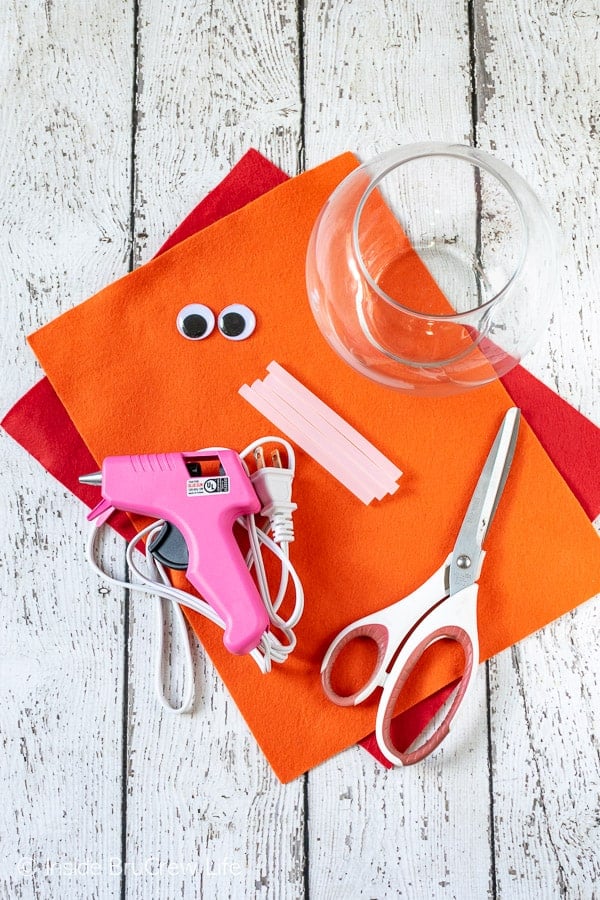 Overhead pictures of felt, glue gun, clear jar, and googly eyes to make a turkey jar.