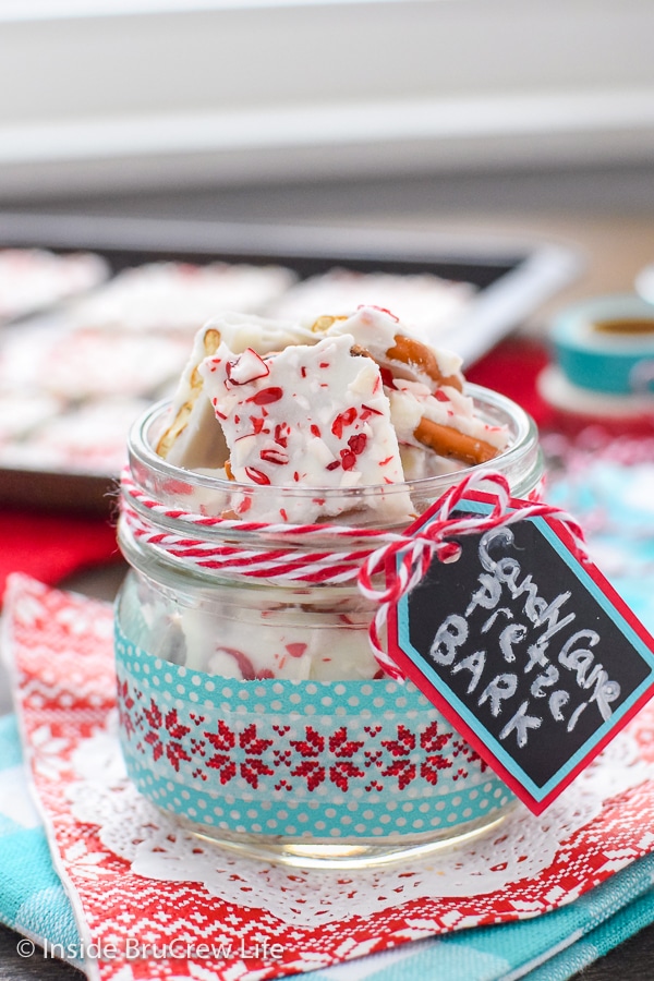 A red and teal towel with a clear jar filled with candy cane pretzel bark on it