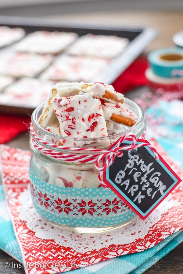 A clear jar filled with candy cane pretzel bark on a red and blue napkin