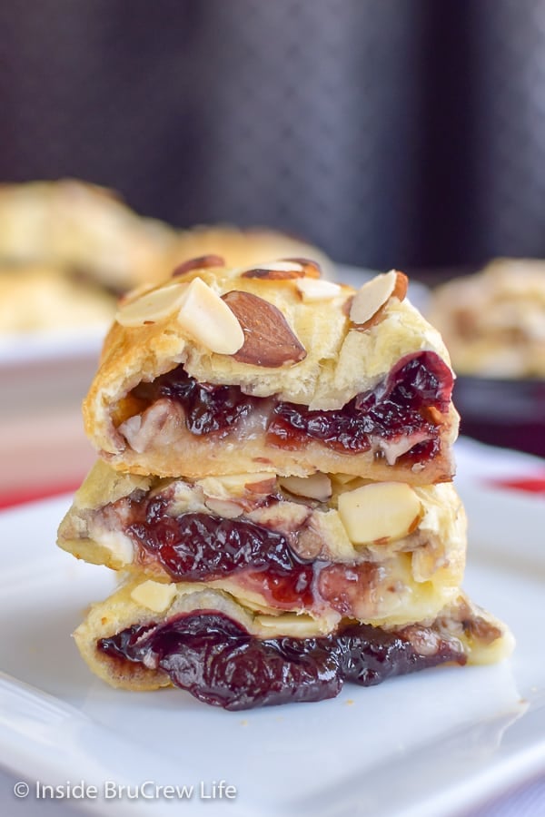 2 cherry almond brie bites stacked together on a white plate.