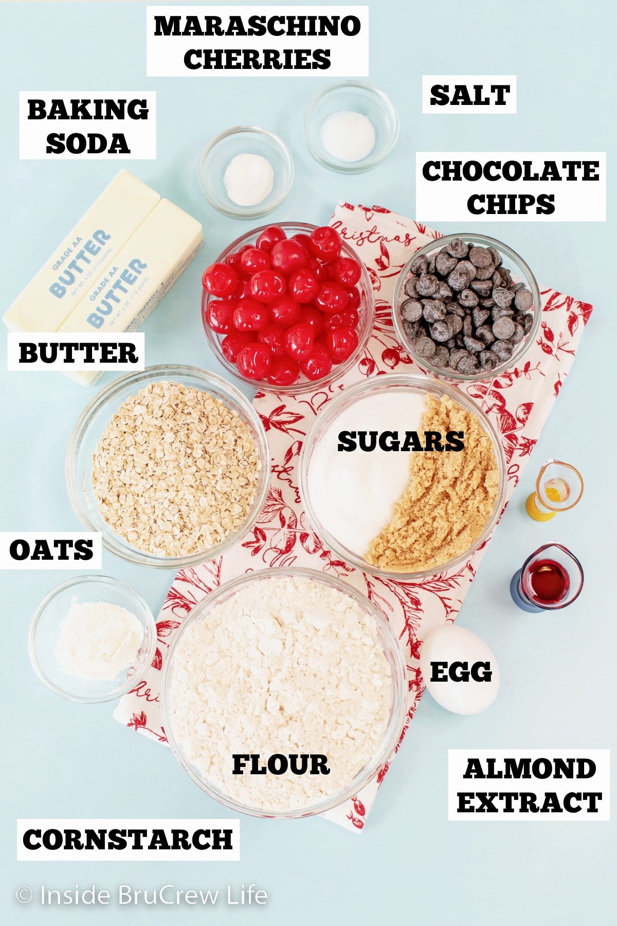 A blue board with bowls of ingredients needed to make chocolate chip cookies with cherries.