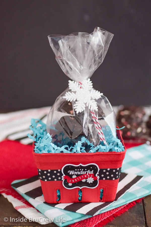 A red berry basket filled with a bag of chocolate peppermint cookies tied shut with twine and a snowflake.