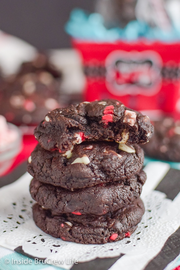 Four chocolate peppermint cookies stacked on top of each other with a bite out of the top cookie.
